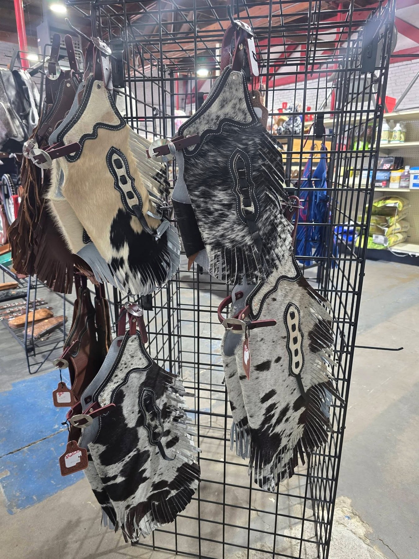 Fringed cowhide chaps hanging on a rack in the shop