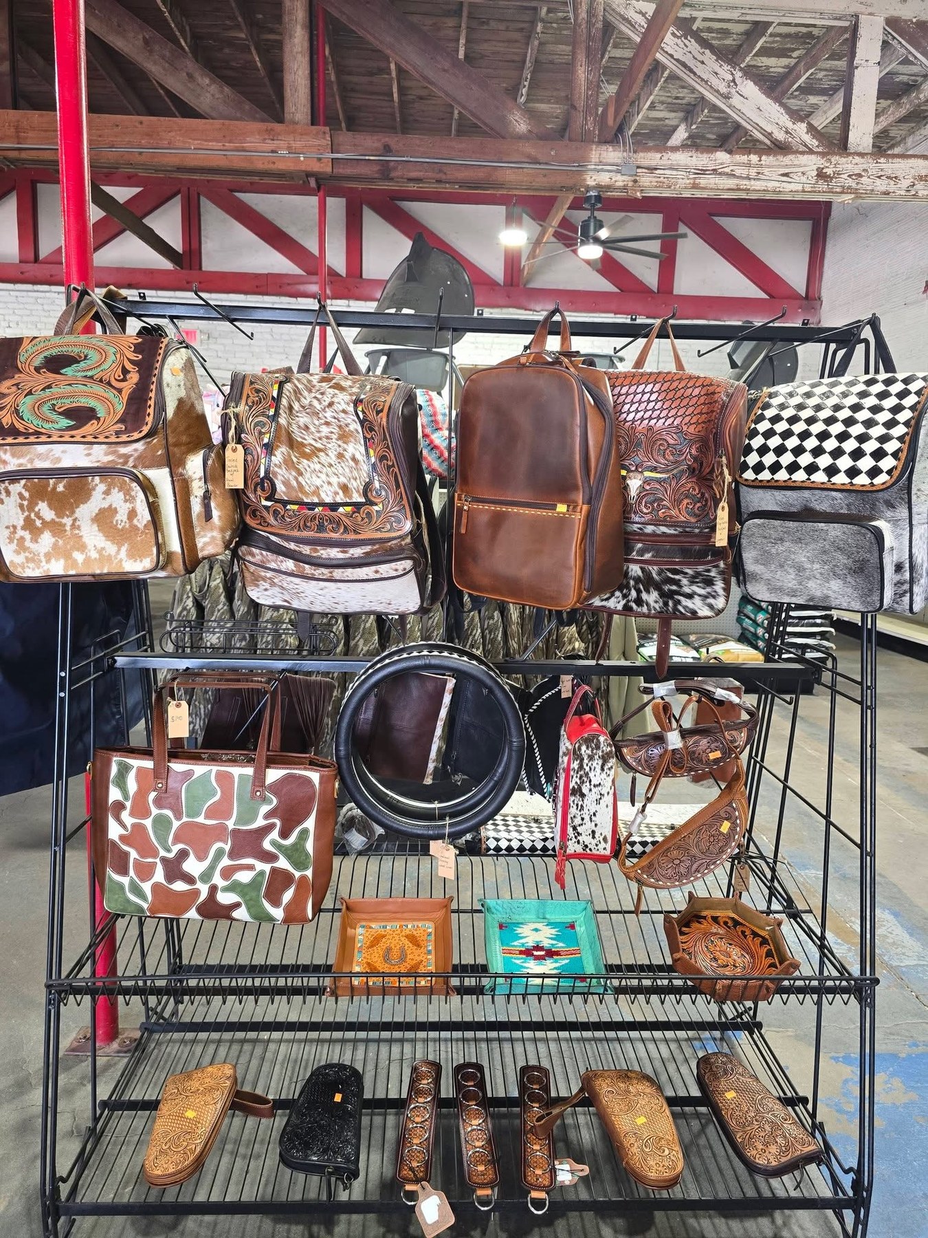 Western leather backpacks, cowhide bags, and tooled accessories on the shop rack