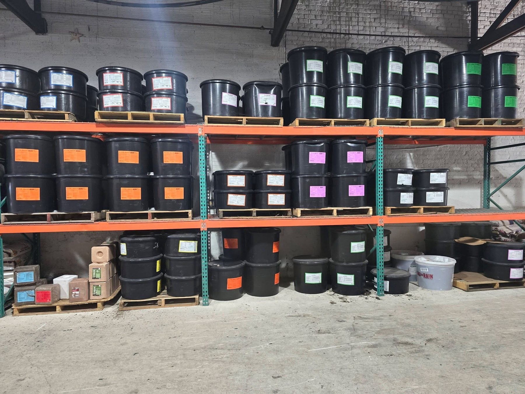 Black mineral and protein lick tubs stacked on the warehouse racks